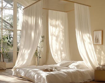 May include: A canopy bed with white curtains and bedding. The bed is low to the ground and has a wooden frame. Sunlight streams through a large window, illuminating the room. A small framed picture hangs on the wall.