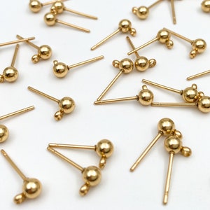 May include: A collection of gold-toned earring findings with a single ball or two balls at the end of each post.