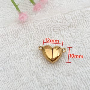 May include: A gold-colored heart-shaped magnetic clasp for jewelry making. The clasp measures 12mm wide and 10mm high.