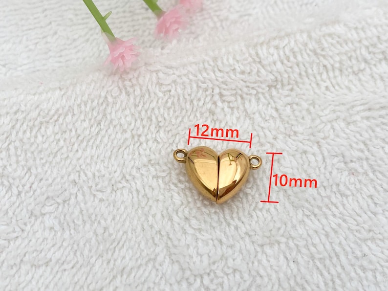 May include: A gold-colored heart-shaped magnetic clasp for jewelry making. The clasp measures 12mm wide and 10mm high.