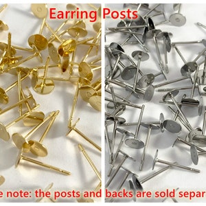Op de afbeelding: Een close-up afbeelding van een grote hoeveelheid gouden en zilveren oorbelstiften. De stiften zijn gemaakt van metaal en hebben een platte, ronde basis. De tekst "Earring Posts" staat in rode letters bovenaan de afbeelding. De tekst "please note: the posts and backs are sold separately" staat in rode letters onderaan de afbeelding.