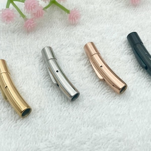 May include: Four metal bracelet clasps in different finishes: silver, gold, rose gold, and black. The clasps are curved and have a smooth finish.