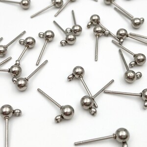 May include: A group of silver-toned earring posts with small round balls on the end. The posts are designed for use with jewelry making.