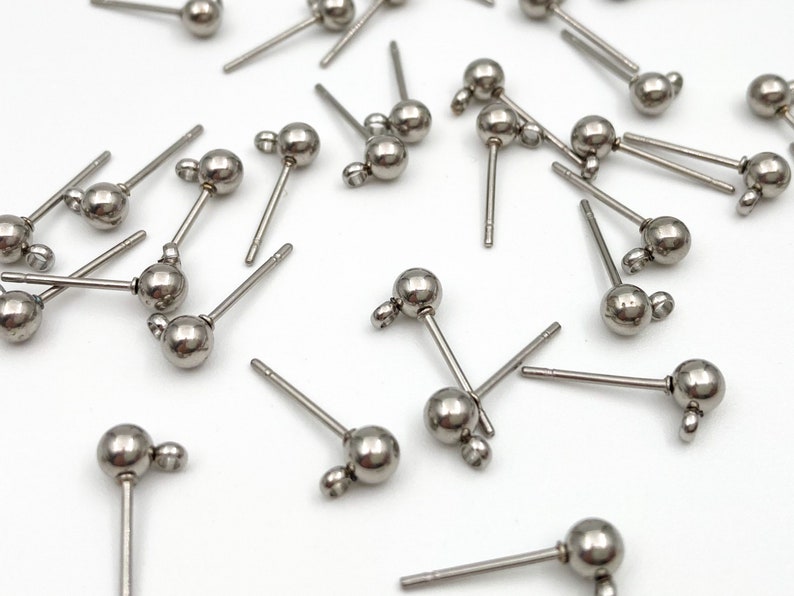 May include: A group of silver-toned earring posts with small round balls on the end. The posts are designed for use with jewelry making.