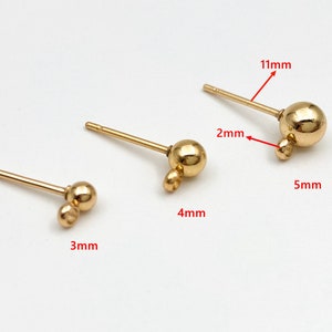 May include: Three gold-toned earring findings with different sized ball charms. The smallest finding is 3 mm long, the middle finding is 4 mm long, and the largest finding is 11 mm long.