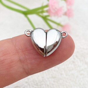 May include: Silver heart-shaped magnetic clasp for jewelry making. The clasp is made of two pieces that fit together to create a secure closure.