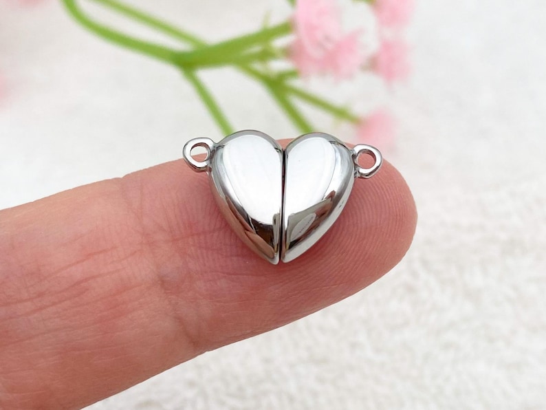 May include: Silver heart-shaped magnetic clasp for jewelry making. The clasp is made of two pieces that fit together to create a secure closure.