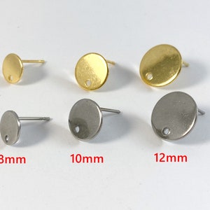 May include: Three pairs of earring findings in gold and silver. The findings are round and have a small hole in the center. The findings are 8mm, 10mm, and 12mm in diameter.