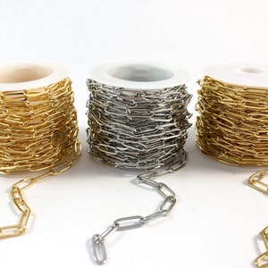K&ouml;nnte beinhalten: Drei Spulen Kette, eine gold, eine silber und eine messingfarben, mit einer L&auml;nge der Kette, die von jeder Spule ausgeht.