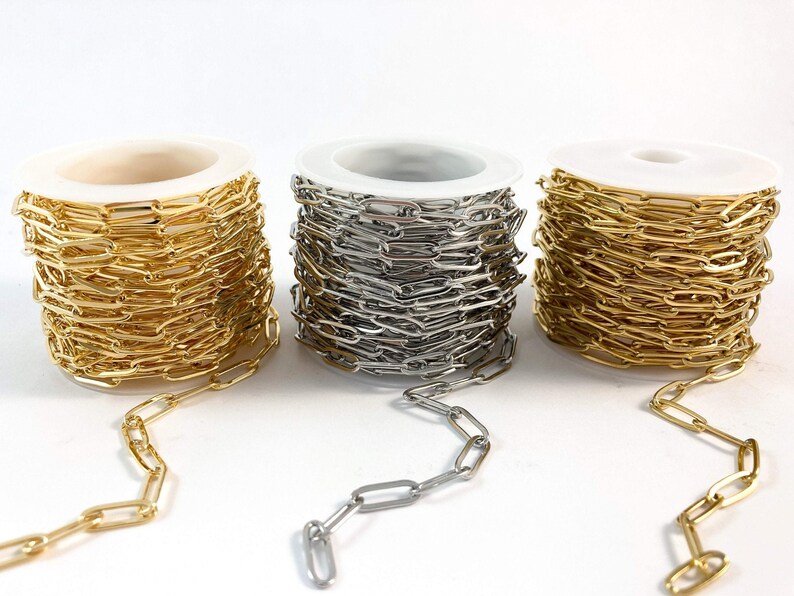 K&ouml;nnte beinhalten: Drei Spulen Kette, eine gold, eine silber und eine messingfarben, mit einer L&auml;nge der Kette, die von jeder Spule ausgeht.