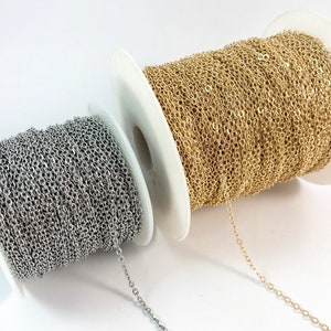 May include: Two spools of chain, one silver and one gold, are shown on a white background. The chain is wound around the spools, and a length of chain is hanging off each spool.