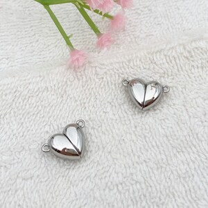 May include: Two silver heart-shaped magnetic clasps for jewelry making. The clasps are open and ready to be attached to a necklace or bracelet.
