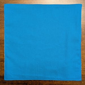 May include: A solid blue fabric square with a stitched edge.