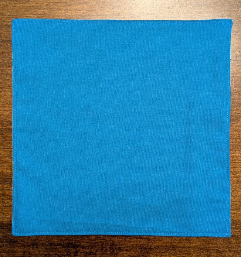 May include: A solid blue fabric square with a stitched edge.
