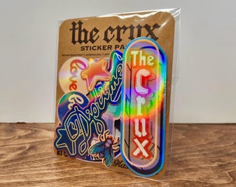 May include: A sticker pack with various holographic stickers. The stickers include the text "the crux", "Love", "Picture", and "The Crux". The stickers are in a clear plastic sleeve and are on a brown cardboard backing.