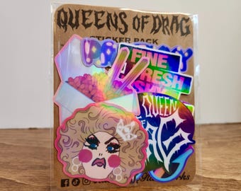 May include: A sticker pack titled QUEENS OF DRAG on a brown card backing. The stickers feature holographic finishes, including a drag performer with blonde hair, a takeout container with chopsticks, and text reading FINE FRESH FUN and QUEEN OF DRAG.