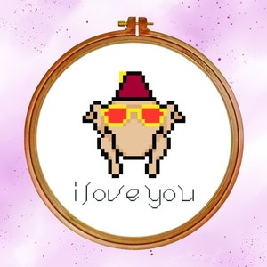 May include: A white embroidery hoop with a pixelated image of a turkey wearing sunglasses and a red hat. The text "i love you" is below the turkey.