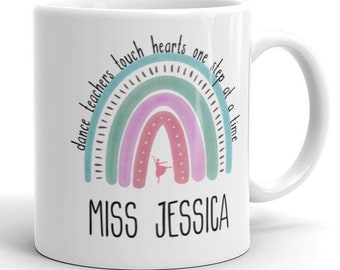Może przedstawiać: Biały ceramiczny kubek z pastelowym tęczowym wzorem i napisem "dance teachers touch hearts one step at a time". Imię "MISS JESSICA" jest wydrukowane poniżej. Mała baletnica znajduje się w środku tęczy.