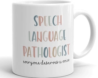 Op de afbeelding: Witte keramische mok met de woorden "SPEECH LANGUAGE PATHOLOGIST" in pastelkleuren. Daaronder staat de zin "everyone deserves a voice". De mok heeft een gebogen handvat en staat tegen een witte achtergrond.