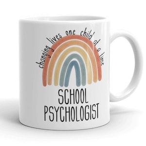 May include: White ceramic mug with a rainbow design and the text "Changing lives one child at a time School Psychologist".