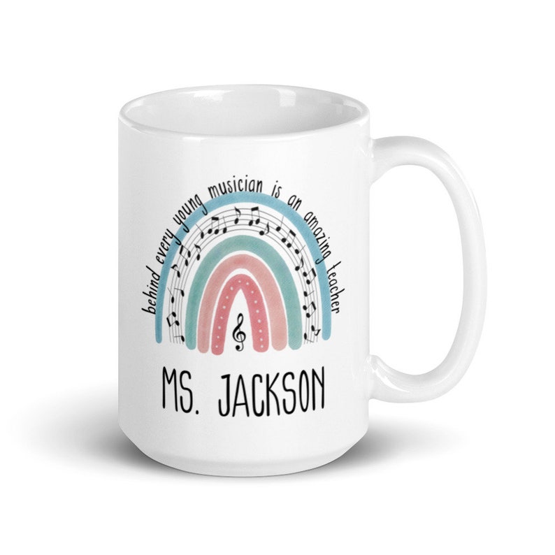 Może przedstawiać: Biały kubek ceramiczny z wzorem tęczy ozdobionym nutami i tekstem "Behind every young musician is an amazing teacher." Kubek ma r&oacute;wnież nadrukowane imię "MS. JACKSON".