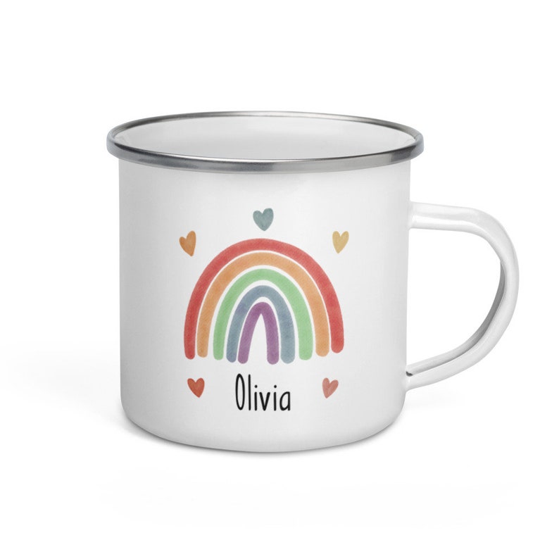 May include: White enamel mug with a rainbow and hearts design. The mug has a silver rim and handle. The text "Olivia" is printed on the mug.
