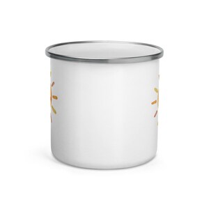 K&ouml;nnte beinhalten: Wei&szlig;e Emaille-Tasse mit einem bunten Sonnendesign auf jeder Seite. Die Tasse hat einen silbernen Rand.
