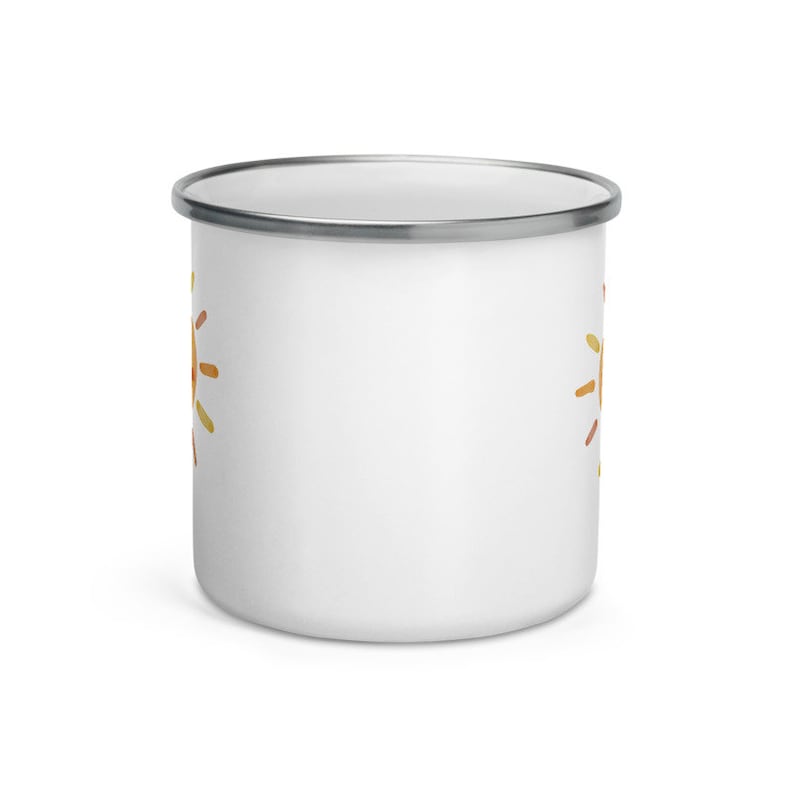 K&ouml;nnte beinhalten: Wei&szlig;e Emaille-Tasse mit einem bunten Sonnendesign auf jeder Seite. Die Tasse hat einen silbernen Rand.