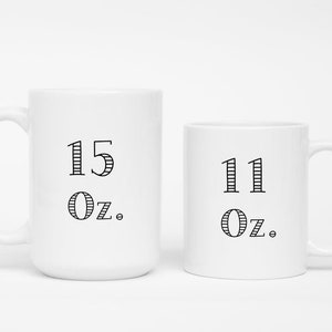 May include: Two white ceramic mugs. The larger mug has "15 Oz." printed in black, and the smaller mug has "11 Oz." printed in black. Both mugs have a simple, clean design.