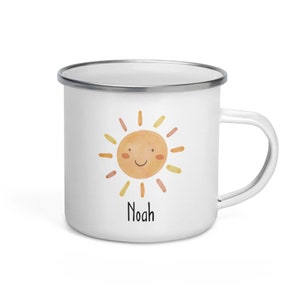 K&ouml;nnte beinhalten: Wei&szlig;e Email Tasse mit einer l&auml;chelnden Sonnenillustration und dem Namen "Noah" darunter gedruckt.