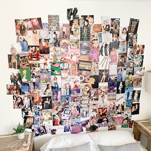 May include: A white wall covered in a collage of photos from the 1990s and early 2000s. The photos feature celebrities, fashion, and pop culture trends of the era. The collage is above a bed with white bedding and two grey patterned pillows.