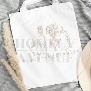 May include: White tote bag with a brown outline of vegetables and the text "The Homely Avenue Fresh Vegetables".
