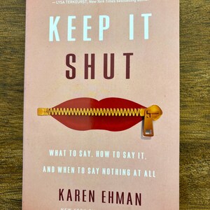 May include: A book cover with the title "KEEP IT SHUT" in large white letters. The cover features a red mouth with a gold zipper. The author's name, Karen Ehman, and the text "New York Times Bestseller" are also visible.