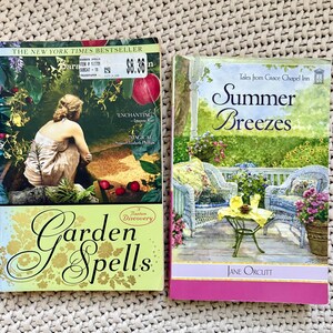 May include: Two paperback books. "Garden Spells" by Sara and "Summer Breezes" by Jane Orcutt. "Garden Spells" has a woman on the cover, with a green and gold title. "Summer Breezes" has a porch scene with wicker furniture.