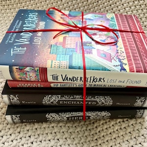 Könnte beinhalten: Ein Stapel von vier Büchern, die mit einem roten Band zusammengebunden sind. Das oberste Buch trägt den Titel "The Vanderbeekers Lost and Found" mit einer farbenfrohen Stadtillustration. Darunter befindet sich "Pip Bartlett's Guide to Magical Creatures". Die unteren beiden Bücher sind schwarz mit goldener Schrift.