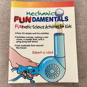 May include: A book titled "Mechanics Fundamentals" with the subtitle "FUNtastic Science Activities for Kids." The cover shows a cartoon illustration of a blue hairdryer with two floating balls. The book promises over 25 simple and fun activities.