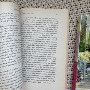 May include: Open book with text from "Garden Spells" by Sarah Addison Allen. The page is open to chapter 167. A bookmark with a floral design is visible on the right side of the book.