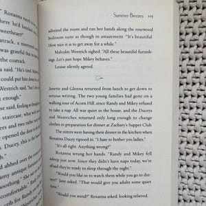 May include: Open book with text on a white page. The text includes the title "Summer Breezes" and dialogue between characters. The book is open on a textured surface.