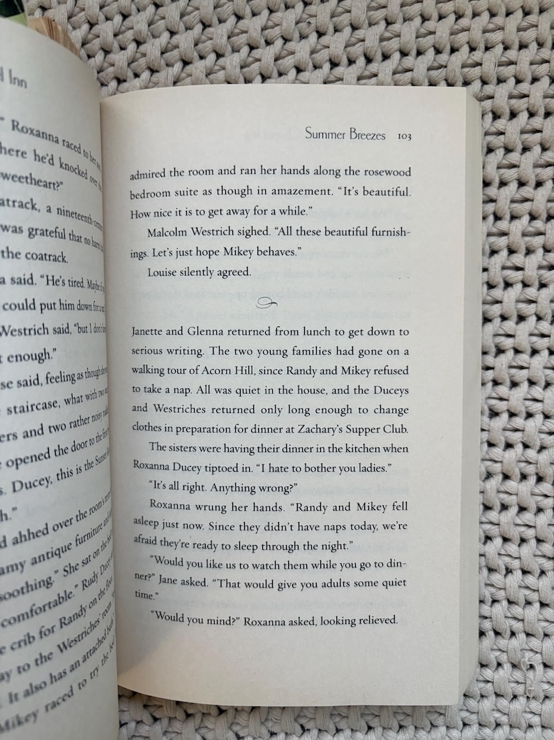 May include: Open book with text on a white page. The text includes the title "Summer Breezes" and dialogue between characters. The book is open on a textured surface.