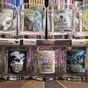 May include: A set of eight clear glass tumblers with Pokemon game cartridge designs. The tumblers feature various Pokemon games, including Pearl, Diamond, Platinum, Black, White, and White 2.