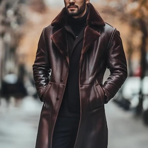 May include: A long, dark brown leather coat with a faux fur collar. The coat has a double-breasted design and pockets. The person is wearing a black turtleneck and black pants. The coat appears to be knee-length.