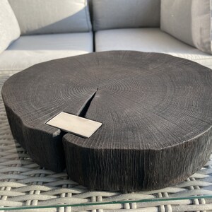 May include: A dark wood serving tray with a natural edge and a metal inlay. The tray is round and has a rustic look.