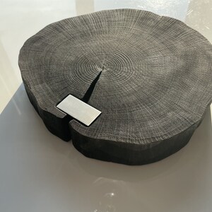 May include: A large, round, black wooden serving tray with a natural wood grain pattern. The tray has a silver metal inlay in the center.