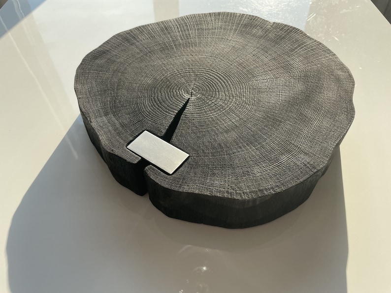 May include: A large, round, black wooden serving tray with a natural wood grain pattern. The tray has a silver metal inlay in the center.