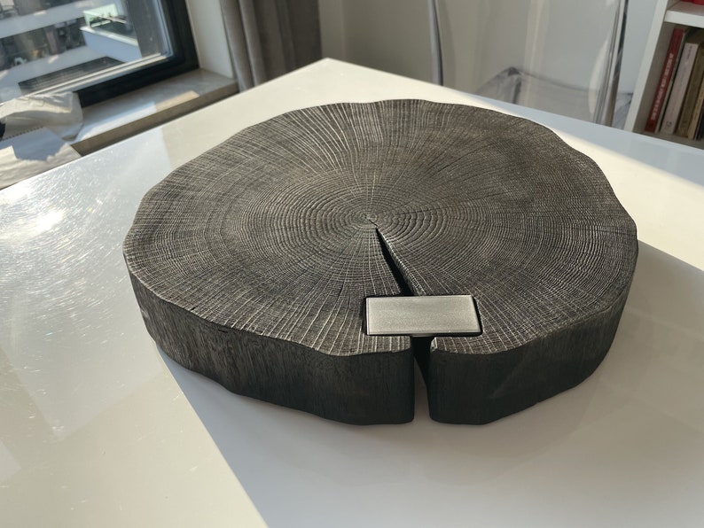 May include: A large, round, dark wood serving tray with a natural wood grain pattern. The tray has a metal accent in the center.