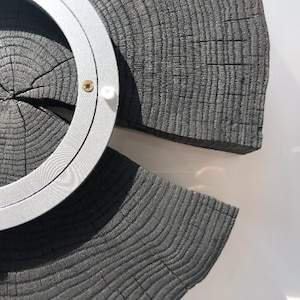May include: A circular wooden wall decor with a silver metal ring around the center. The wood is dark gray and has a natural wood grain pattern.