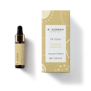 Könnte beinhalten: Eine kleine braune Glasflasche mit goldenem Deckel und Tropfer. Die Flasche ist mit dem Text "BONORDEN ESSENTIALS IKIGAI FINDING PURPOSE" beschriftet. Die Flasche steht auf einer weißen Oberfläche. Die Flasche befindet sich neben einer Schachtel mit einem ähnlichen Etikett. Die Schachtel ist gelb mit einem weißen Sonnendesign.