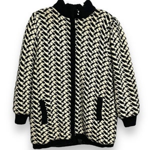 May include: Black and white patterned zip-up sweater with a high collar and two pockets.