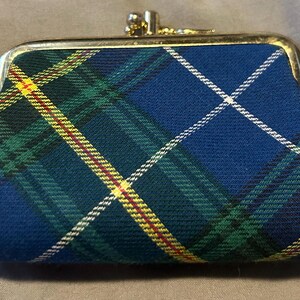 May include: A small coin purse in a blue tartan pattern, with green, yellow, and white accents. The purse has a gold-coloured clasp. The fabric is a classic plaid design.