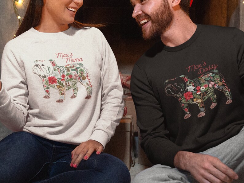 Peut inclure: Deux sweatshirts, un gris clair et un noir, avec un motif de bouledogue floral. Le texte "Max's Mama" et "Max's Daddy" est en rouge. Le motif du bouledogue comprend des &eacute;l&eacute;ments floraux rouges, blancs et verts.